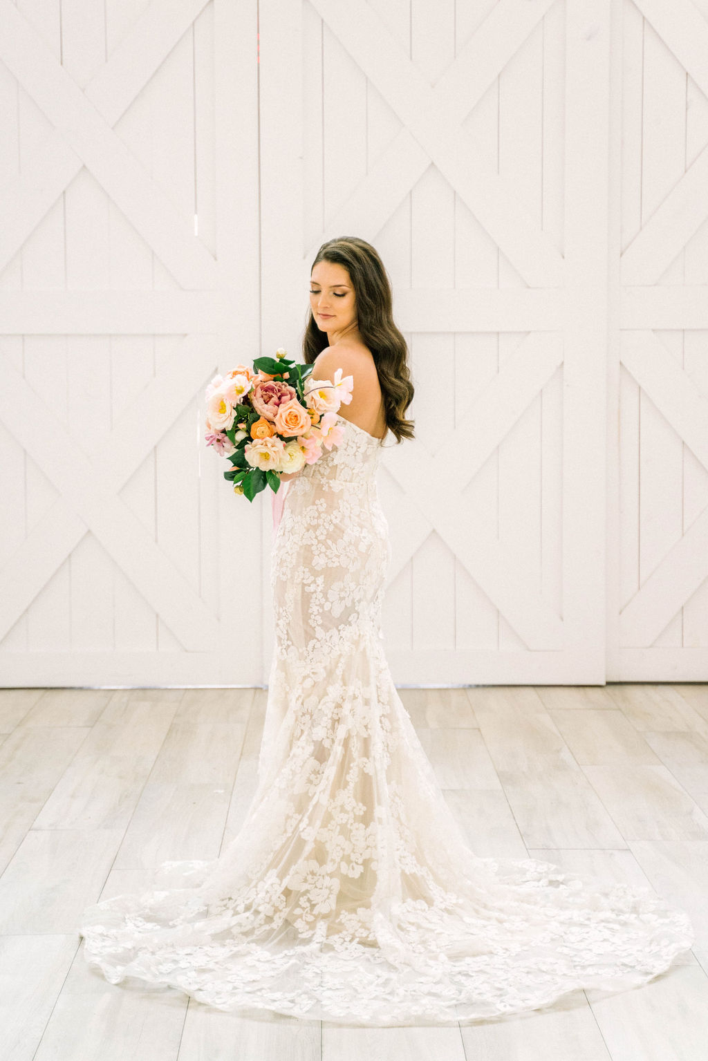 bride wearing lace gown holding peach bridal bouquet